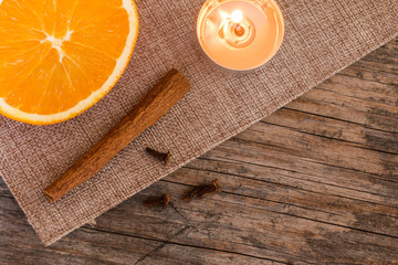 Weihnachtshintergrund: Orange, Zimt, Nelken und Teelicht auf Holzuntergrund