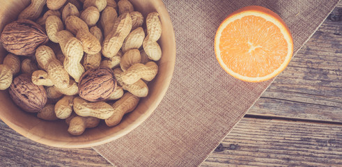 Nüsse und Orange auf rustikalem Holztisch, retro widescreen