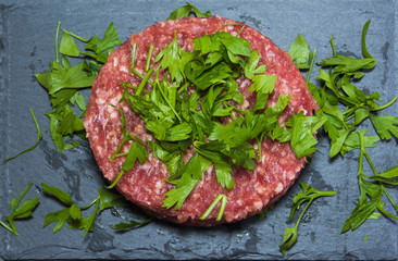 Raw hamburgers with parsley on a stone slate