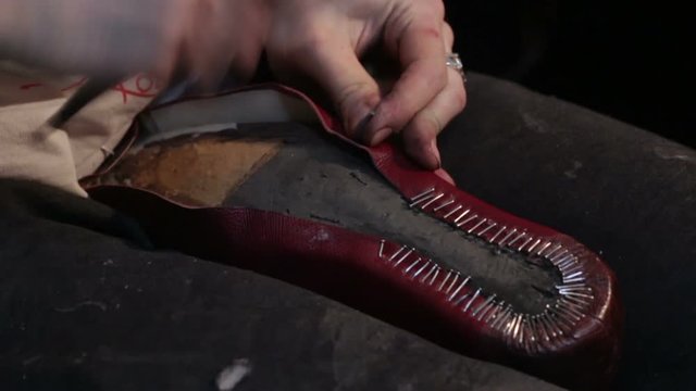 Shoemaker sews shoes, hammering sole