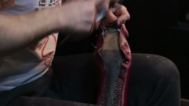 Shoemaker sews shoes, hammering sole