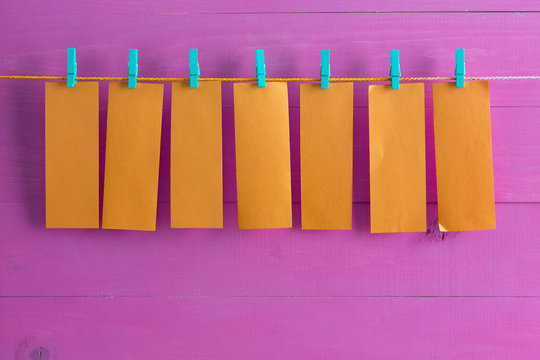Blank orange note pad sheets hanging from string