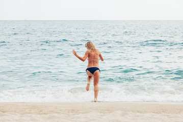 Young woman running into the sea

