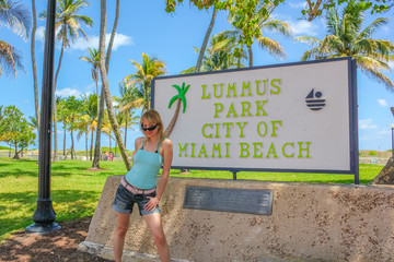 Smiling tourist posing in front of Lummus Park in South Beach in Miami Beach. This beachfront park...