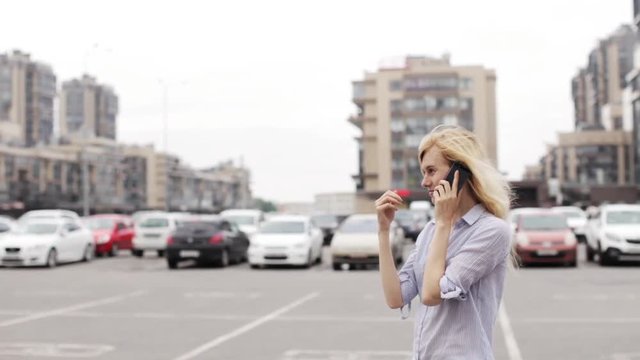Girl Talking on the Phone While Standing on Street Parking on the Background of Houses