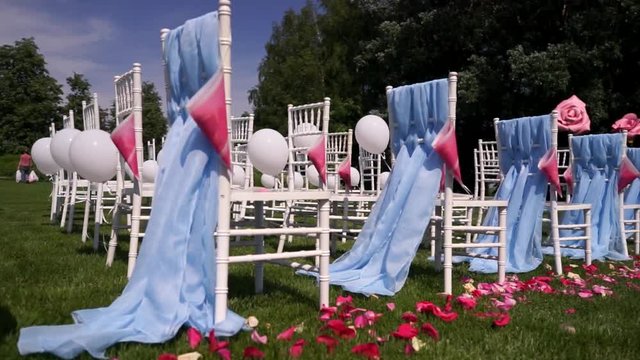 Red rose petals for wedding ceremony in the open countryside, summer, warm weather, Chiavari chairs.