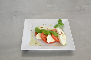 Caprese salad with tomatoes, basil and mozzarella on the table of stainless steel