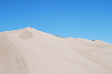 Fototapeta na wymiar Footprints and hikers walking on the crest of High dune in Great Sand Dunes National Park, CO, USA