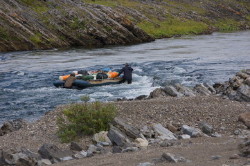 Two travelers ascend the rapids with inflatable catamaran. Small Usa river, Polar Urals.