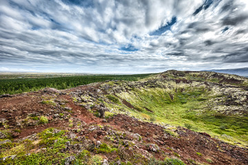 Icelandic landscape with moss, grass and beautiful cloudy sky
