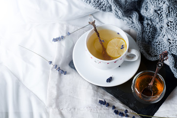 tray with honey and a cup of hot tea in the bed