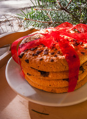 Stack of Christmas cookies tied with red festive ribbon. Next to the Christmas tree branch