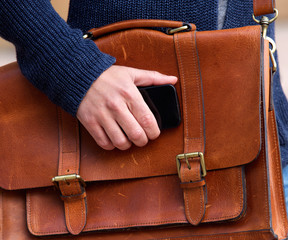 Man with leather bad holding mobile phone