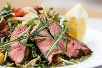 Roast beef with arugula, vegetables and lemon sliced, lies on th