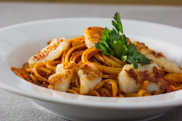 Pasta (spaghetti) with scallops and tomato sauce is on the plate