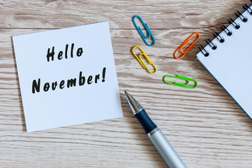 Hello November. hand drawn lettering on notepad at the workplace. Top view
