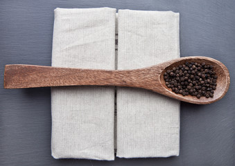 Pepper on spoon and kitchen towel on stone board