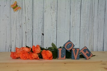 Blocks with the word love and lots of roses wall before Wood