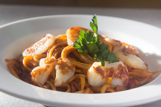 Pasta (spaghetti) with scallops and tomato sauce is on the plate