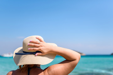 Fototapeta na wymiar Woman with straw hat at the beach