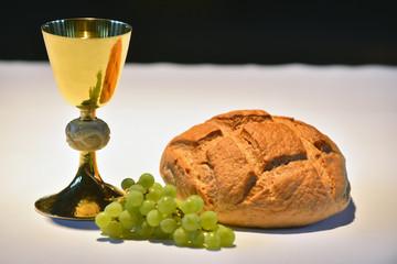 Beautiful golden chalice with grapes and bread on the altar..