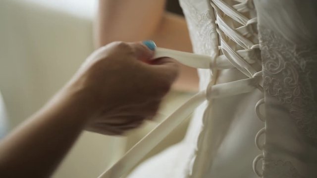 Close up view of woman tighten corset of wedding dress.