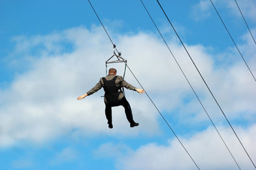 Man in formal suit descends on a zipline