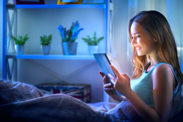 Beauty girl using tablet pc in her bed at night - Powered by Adobe