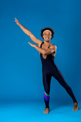 Obraz premium Sportive african man warming up, training over blue background.