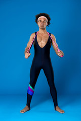 Obraz premium Sportive african man posing with skipping rope over blue background.