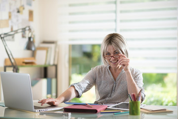 Obraz premium a nice retired woman with gray hairs sitting at her desk,