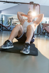 Naklejka na ściany i meble Male fitness model doing sit ups and crunches exercising abdomin