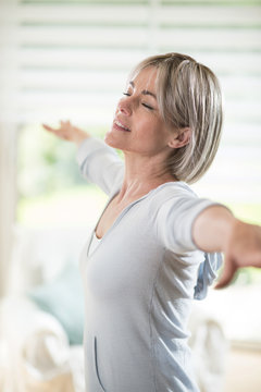 A 50 Year Old  Woman Who Does Yoga, Eyes Closed In Her House