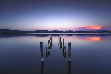La jetée ou la jetée en bois reste sur un coucher de soleil bleu du lac et un reflet du ciel