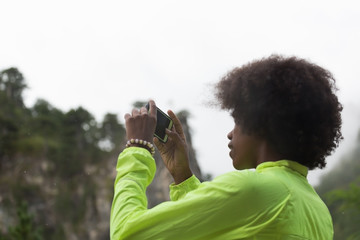 Fototapeta premium Beautiful afro american woman taking photos outdoors in a forest