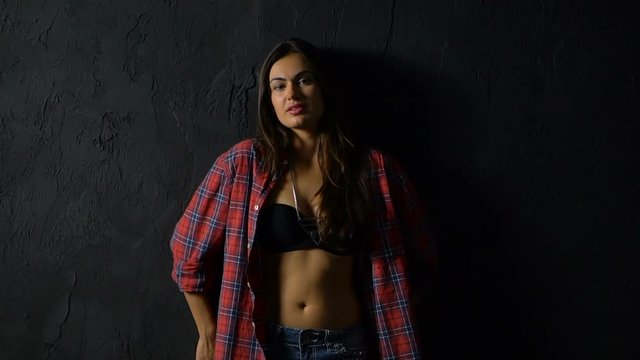 Girl brunette in red plaid shirt and denim shorts on black background