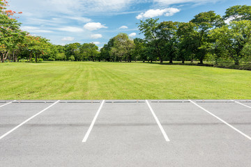 Empty parking lot against green lawn in city park