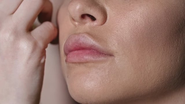 Closeup of hands of professional makeup artist using brush and powder to outline eyebrow of model