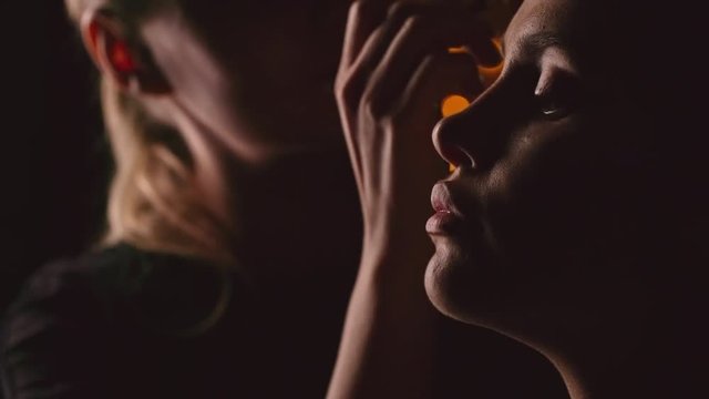  Professional makeup artist using brush to outline eyebrows of young model while working in dark studio with illumination in the background