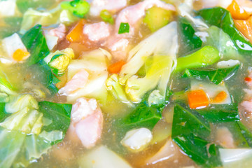 Closeup to fried noodle with pork and kale soaked in gravy.