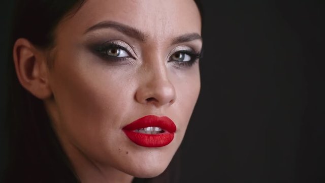 Attractive young woman with red lips touching her hair and looking at the camera
