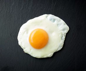 Foto op Plexiglas Spiegeleieren gebakken ei op zwarte achtergrond