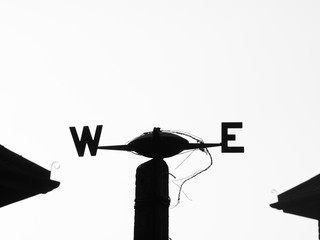 Old weathervane pointing West and East