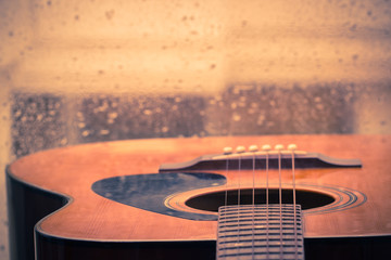 Naklejka premium Acoustic guitar next the window with drop water