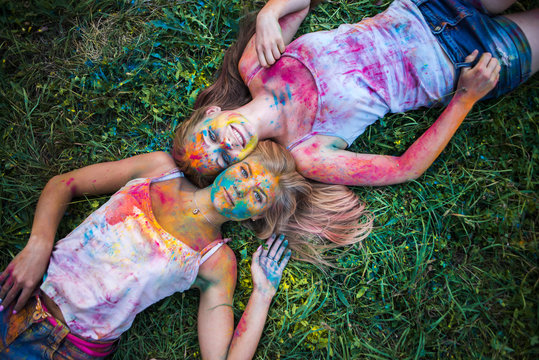 girls celebrate Indian holi festival with colorful paint powder on faces and body