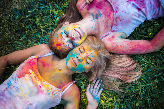 girls celebrate Indian holi festival with colorful paint powder on faces and body