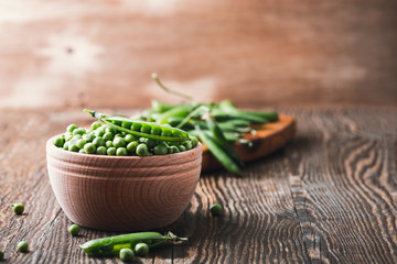 Green peas in wooden bowl on  rural background