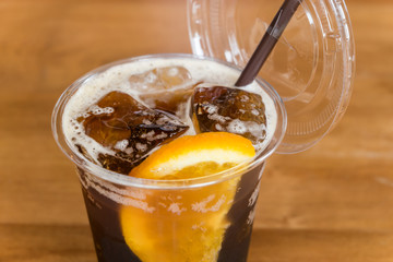 Glass of iced orange tonic lemon tea with slice of orange on wooden table