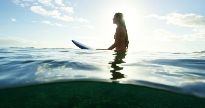 Beautiful surfer girl enjoying sunset surf