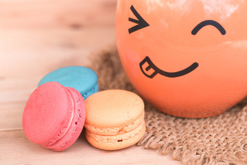 macarons sweet beauty dessert with smile wrinkle face mug on wood background pink color tone.